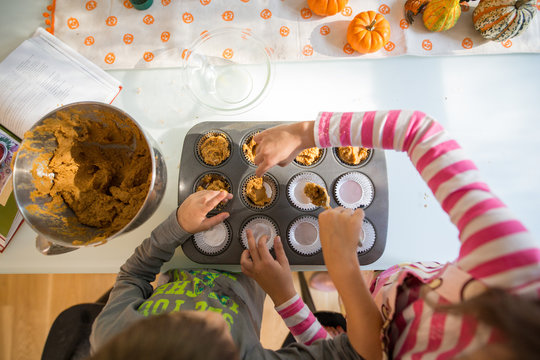 Children measuring out mixture into baking cases