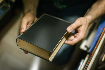 Curious man choosing book in his library at home
