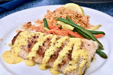 Grilled mahi-mahi drizzled with creamy sauce served with a side of rice and mixed vegetables