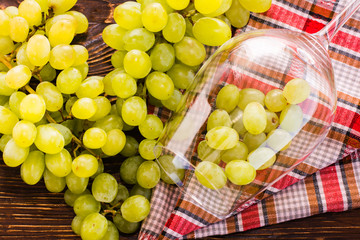 The grapes in the wine glass and bunch of grapes on the table