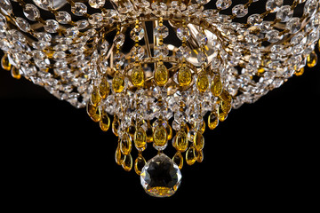 Large crystal chandelier close-up in baroque style isolated on black background.