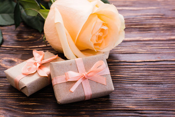 Пара упакованных подарков и свежая роза на деревянном столе