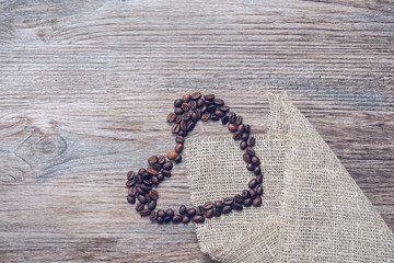 Heart of coffee beans on a wooden background.