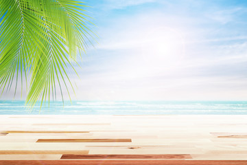 Empty wooden table and palm leaves with party on beach blurred background in summer time.