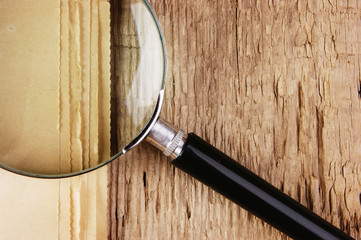edge of the old newspaper and magnifying glass on a wooden background