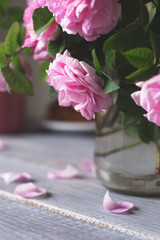Bouquet of rose hips in a glass jar on a white wooden table