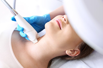 Fotoodmładzanie skóry szyi. Kobieta w klinice medycyny estetycznej na zabiegu laserowego odmładzanie skóry. - obrazy, fototapety, plakaty