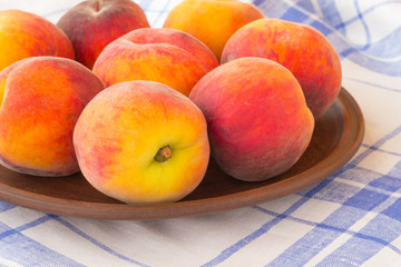 Peaches on a blue and white tablecloth.