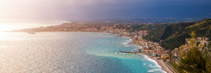 Naxxos, Sicily - Panoramic skyline view of Giardini Naxxos town and beach with turquoise sea water and pine trees in front