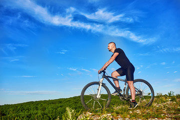 Fototapeta na wymiar Young cyclist riding the bike on the beautiful summer mountain trail.