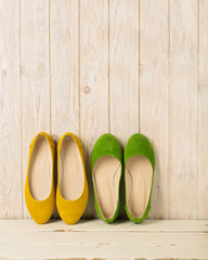 Green and yellow women's shoes (ballerinas) on wooden background.