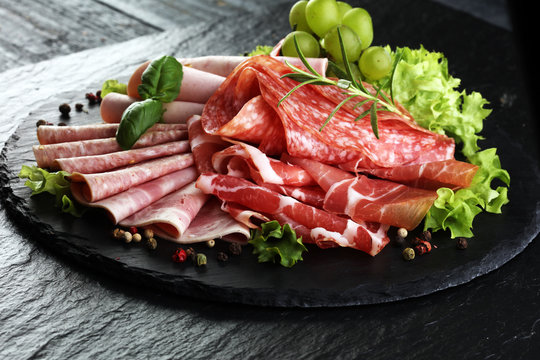 Food tray with delicious salami, pieces of sliced ham, sausage, tomatoes, salad and vegetable - Meat platter with selection