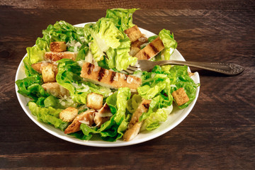 Chicken Caesar salad on rustic background with copyspace