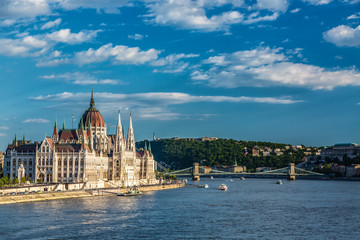 Travel and european tourism concept. Parliament and riverside in Budapest Hungary with sightseeing ships during summer sunny day with blue sky and clouds