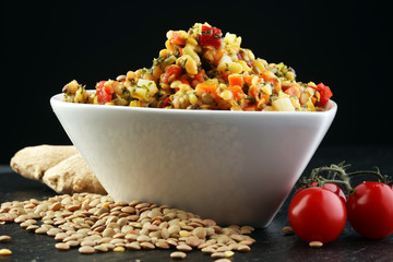 Lentil with carrot and pumpkin ragout in a wooden bowl on a wooden background