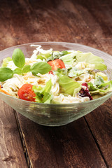 bowl of salad with vegetables and greens on wooden table