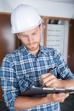 Man In Hardhat Writing On Clipboard