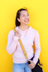 beautiful asian woman against yellow wall and smiling.