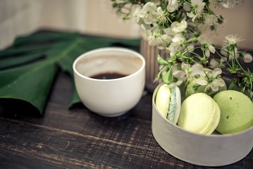 Green macarons on a wood table for coffee or a tea with the blossom flowers on background