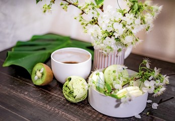 Green macarons on a wood table for coffee or a tea with the blossom flowers on background
