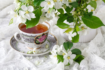 Cup of tea on wooden table and apple blossom. Tea time concept. Breakfast tea cup served with flowers.