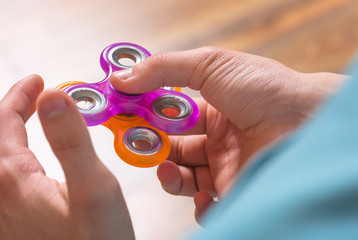 Male child hand holding popular fidget spinner toys - close up. Boy playing with a orange and...