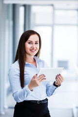 Attractive business woman standing with tablet in her hands and smiling