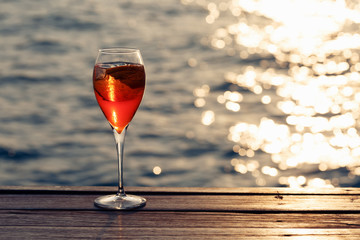 Aperol spritz at a wooden pier at sunset. Luxury resort vacation concept. Festive relax getaway background.