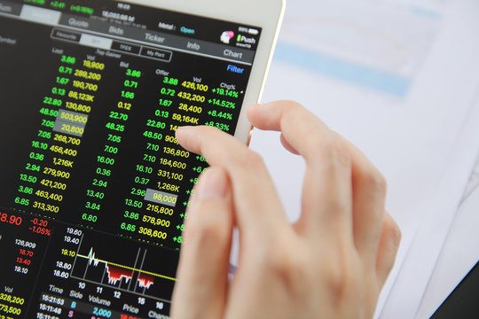 Woman hand Trading online on tablet with business paper and coffee