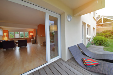 intérieur salon maison rez-de-chaussée donnant sur terrasse en bois 