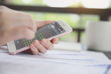 trading online on smartphone with bussiness woman hand