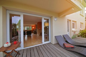 intérieur salon maison rez-de-chaussée donnant sur terrasse en bois 
