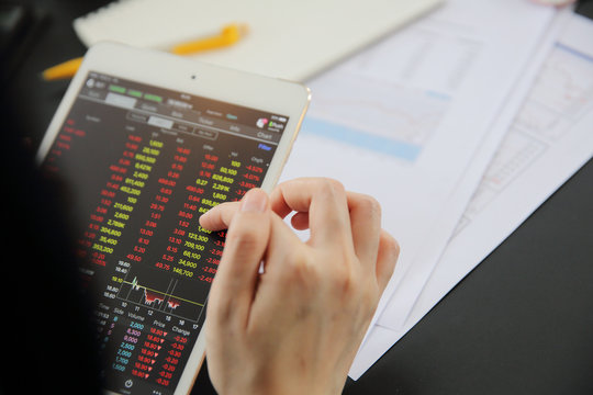 Woman hand Trading online on tablet with business paper and coffee