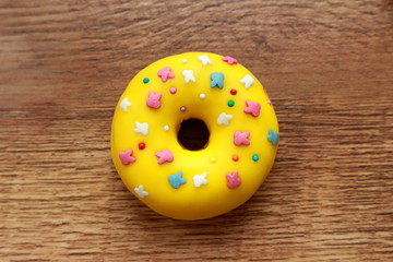 Single yellow donut on a wood background