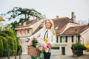 Fototapeta premium Beautiful blond woman standing next to mint color bicycle with big colorful bouquet of flowers in basket