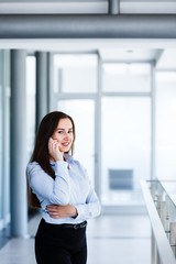 Fototapeta premium Smiling attractive woman standing in modern interior and talking on phone