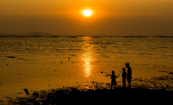 Silhouette of family at sea with sunset sky