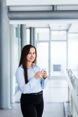 Smiling attractive woman standing in modern interior and talking on phone