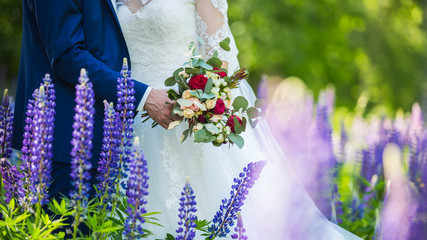 Fototapeta premium hands of the bride and groom with rings on a beautiful wedding bouquet