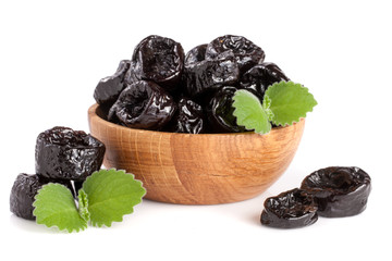 Dried plums or prunes with a mint leaf in wooden bowl isolated on white background