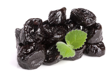 heap of dried plums or prunes with a mint leaf isolated on white background