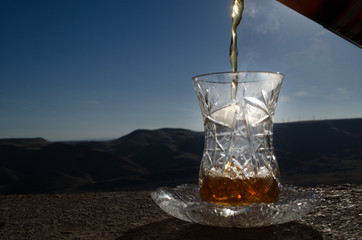 Turkish Azerbaijan tea in traditional glasse and pot outdoor nature background with sunlight and smoke. Eastern tea concept. Armudu traditional cup.