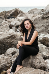 girl sitting on a big rock on a stone beach