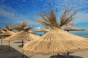 the concept of summer vacation on the beach, straw beach umbrellas at a resort on the ocean