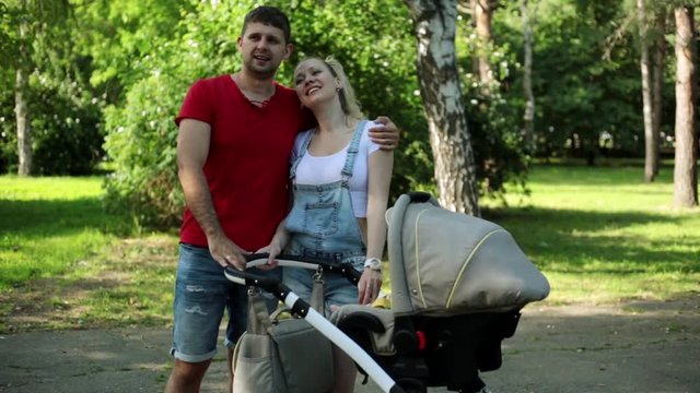 Young parents with a baby stroller. Happy family with baby in park.