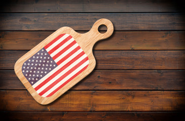 Obraz premium Concept of American cuisine. Cutting board with a American flag on a wooden background