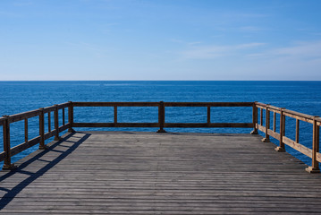 Wooden pier in blue ocean with horizon background. Place for advertising travel, fishing, diving, shipping products. Perfect field with sea, free sky, fresh air.