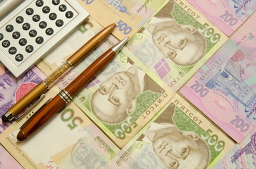 
Two pens and a calculator lie on the banknotes of Ukrainian hryvnia.
