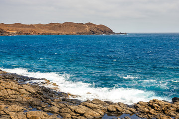 volcanic coastline with wavy ocean and blue sky, Lanzarote island, Spain