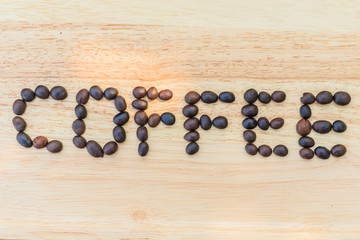 Coffee beans are literally "coffee" on a wooden floor.